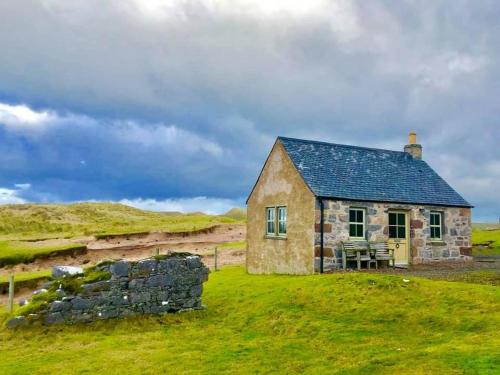 a small stone house on a grassy hill at Balnakeil Beach Bothy in Durness