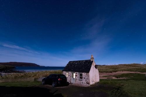 a car parked in front of a small stone house at Balnakeil Beach Bothy in Durness