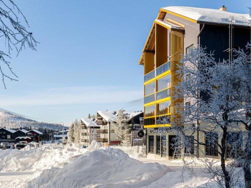 a building covered in snow next to snow covered buildings at Holiday Home Levin kunkku b8 by Interhome in Levi