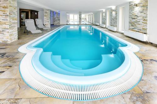 a swimming pool with blue water in a building at Wellness Penzion Life in Číměř