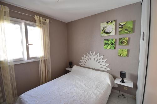 a bedroom with a white bed and a window at Appartement Proche plage in Le Grau-du-Roi