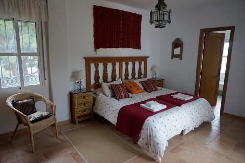 Un dormitorio con una cama y una silla y una ventana. en Finca Sotolindo, en Vejer de la Frontera