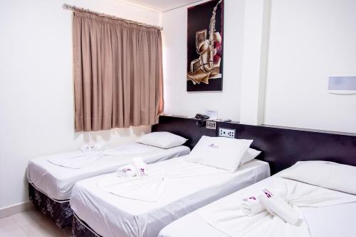 two twin beds in a room with a window at Bougainville Barreiras in Barreiras