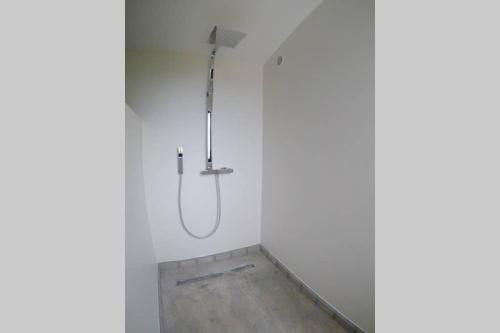 La salle de bains est pourvue d'une douche et d'un mur blanc. dans l'établissement La Baraquette, à Sète