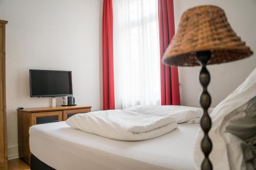 a bedroom with a bed with a lamp and a television at The Dubliner Hotel & Irish Pub in Heidelberg