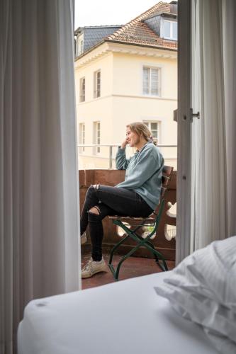 a woman sitting in a chair on a balcony at The Dubliner Hotel & Irish Pub in Heidelberg