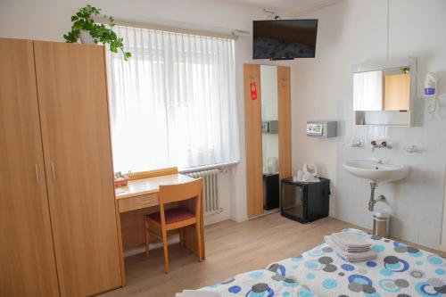 a small room with a desk and a sink at Garni Moderno in Bellinzona