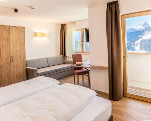 a hotel room with two beds and a couch at Hotel Chi Vai in San Vigilio Di Marebbe