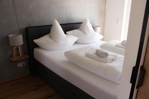 2 Betten mit weißen Kissen und Handtüchern darauf in der Unterkunft Apartment Monolith Black Forest in Schonach