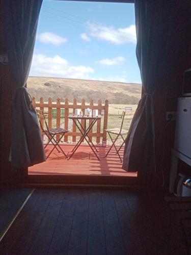 una ventana con vistas a una mesa y un banco en Wee Hoose Glamping 3, en Kinbrace