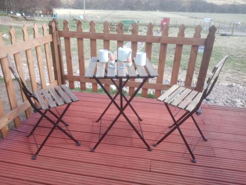 two chairs and a table with cups and mugs on it at Wee Hoose Glamping 3 in Kinbrace