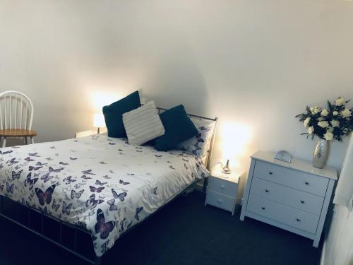 a bedroom with a bed and a table with a vase of flowers at The Cottage in Redruth