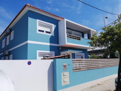 a blue house with a white fence in front of it at Lisbon Beach Apartments 6 in Costa da Caparica