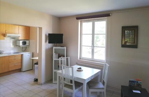 uma cozinha com uma mesa e cadeiras brancas e uma janela em Le MAELY, studio au calme, centre de Honfleur (linge fourni) em Honfleur