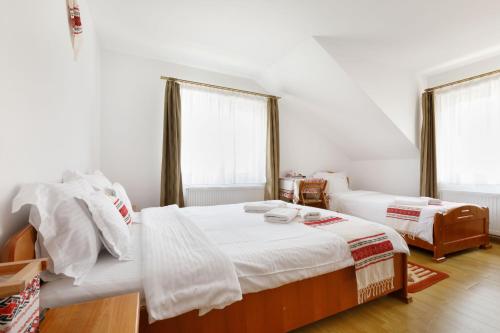 two beds in a room with white walls and windows at Casa Dacică in Râşnov