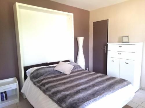 ein Schlafzimmer mit einem Bett mit einer grauen Decke in der Unterkunft Le MAELY, studio au calme, centre de Honfleur (linge fourni) in Honfleur
