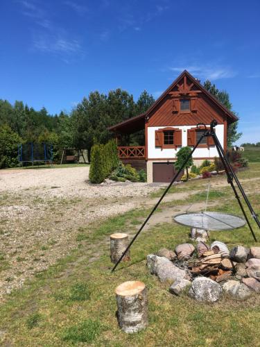 a fire pit in front of a log cabin at Domek w Bartoszymlesie in Stara Kiszewa