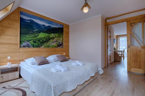 a bedroom with a bed with a large painting on the wall at Pensjonat Dawidek in Zakopane