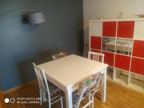 a kitchen with a white table and chairs and a red cabinet at Apartamento DH in Zamora