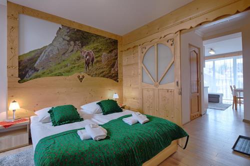 a bedroom with a large bed with green sheets at Pensjonat Dawidek in Zakopane