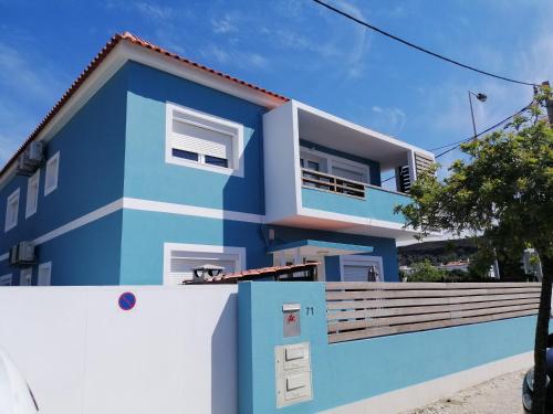 a blue house with a white fence in front of it at Lisbon Beach Apartments 8 in Costa da Caparica