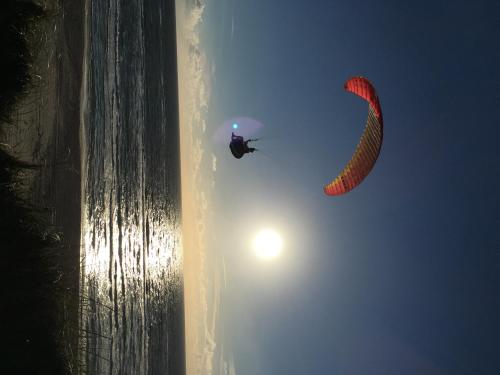 a person is flying a kite in the sky at Løkken Strand Camping (Empty Lot) in Løkken