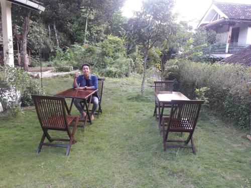 a man sitting at a table in a yard at Griya Harja Homestay in Borobudur