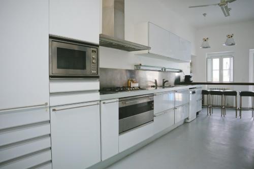 a kitchen with white cabinets and stainless steel appliances at Casas do Sal in Alcácer do Sal
