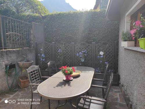 a patio with a table and chairs with flowers on it at Secret Garden Mandello in Mandello del Lario