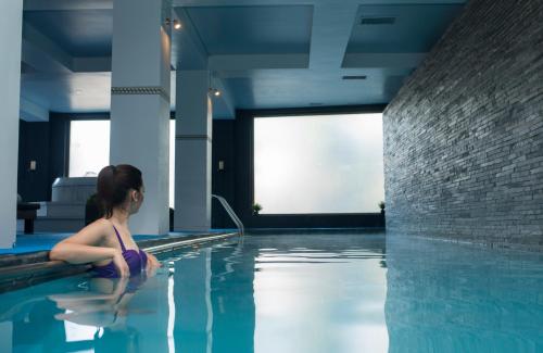 a young girl sitting in a swimming pool at Enjoy Puerto Varas in Puerto Varas