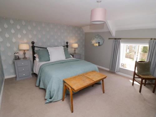 een slaapkamer met een bed, een tafel en een raam bij School House Cottage in York