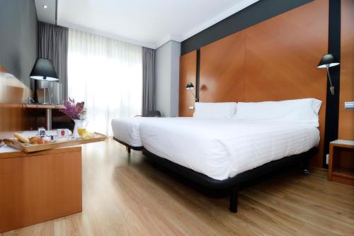 a bedroom with a large white bed with a wooden headboard at Silken Juan de Austria in Valladolid