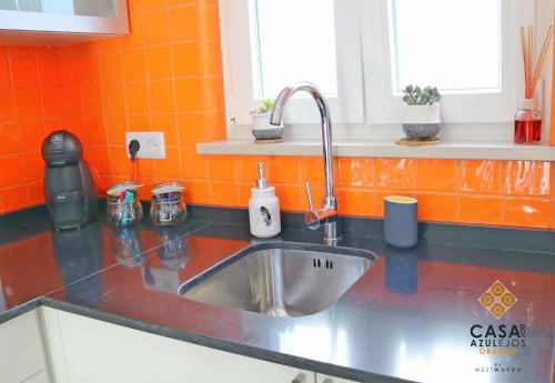 a kitchen counter with a sink and an orange wall at Casa do AZULejo - Orange in Peniche