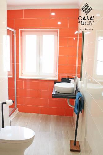 an orange bathroom with a toilet and a sink at Casa do AZULejo - Orange in Peniche