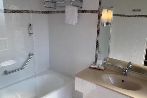 a bathroom with a tub and a sink and a mirror at Best Western de Diane in Nevers