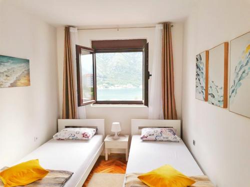 two beds in a room with a window at Ana's Place in Kotor