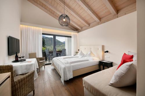 a bedroom with a bed and a couch and a tv at Pension Riedingerhof in Merano