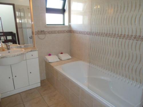 een badkamer met een bad, een wastafel en een spiegel bij Holiday House in Albufeira