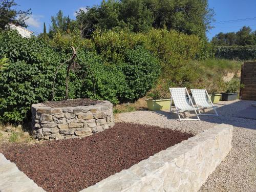 two chairs sitting in a garden with a stone wall at L'Ansolane in Fuveau