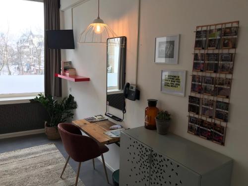 a room with a desk and a table and chairs at Hotel Credible in Nijmegen