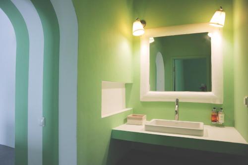 a green bathroom with a sink and a mirror at Casas do Sal in Alcácer do Sal