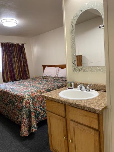 a bathroom with a bed and a sink with a mirror at Madill Inn in Madill