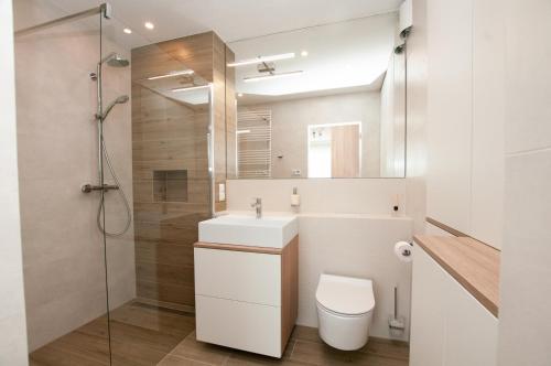 a bathroom with a toilet and a sink and a shower at Komfortowy Apartament PASTELOWY - 2 sypialnie in Kołobrzeg