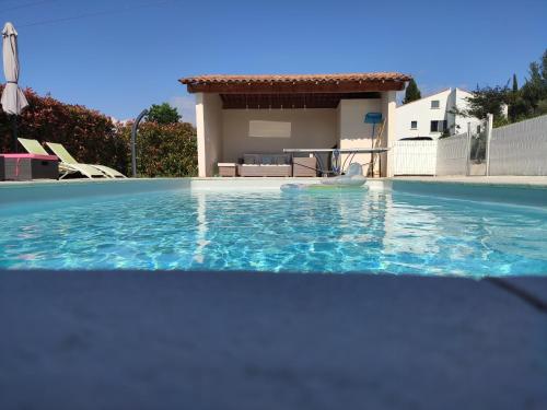 a swimming pool with a house in the background at L'Ansolane in Fuveau