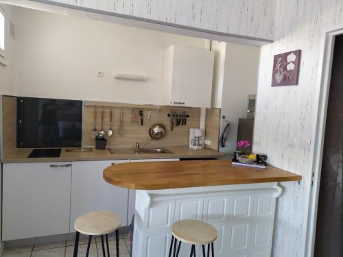 a kitchen with white cabinets and a wooden counter top at Petite halte Appt 103 in Sens