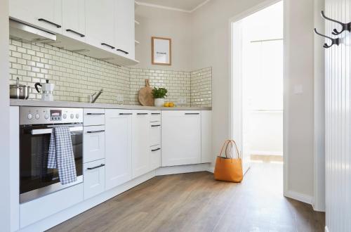 a white kitchen with white cabinets and an orange bag at Villa Fortuna in Ostseebad Sellin