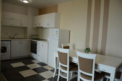 een keuken met witte kasten en een tafel en stoelen bij Flora Beach Private in Pomorie