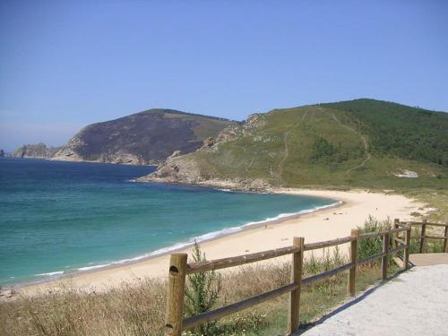 a beach with a wooden fence next to the ocean at Fisterracons in Finisterre
