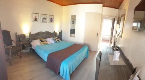 a bedroom with a bed with a blue comforter at Les Jardins du Forez in Montrond-les-Bains