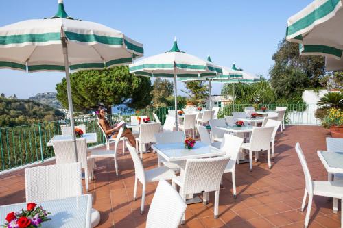 a restaurant with white chairs and tables and umbrellas at Resort Terme La Pergola in Ischia